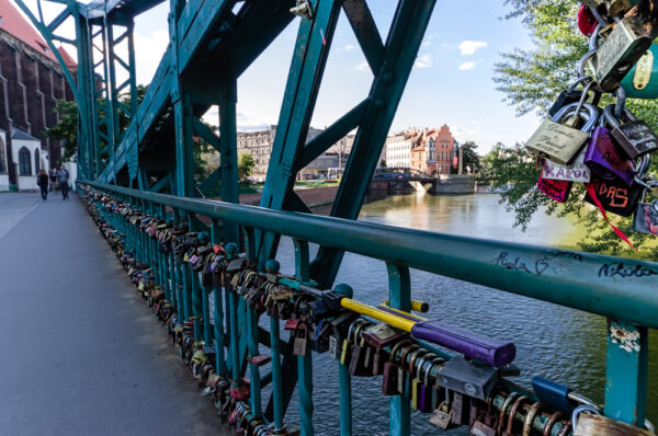 Tumski Bridge (Polish: Most Tumski) is a steel bridge over the north branch of the Oder river in Wrocław, Poland. Constructed in 1889 it replaced an old wooden bridge to connect Ostrów Tumski and Wyspa Piaskowa. Until 1945, its name was Dombrücke. It is an old road bridge now open to pedestrians only. Tumski Bridge is also called Lovers Bridge, Cathedral Bridge or Green Bridge. It's a place of enamoured tradition for lovers. The bridge is full of padlocks which lovers leave to cherish their feelings. An important part of the ceremony is to throw the key into the Odra river.