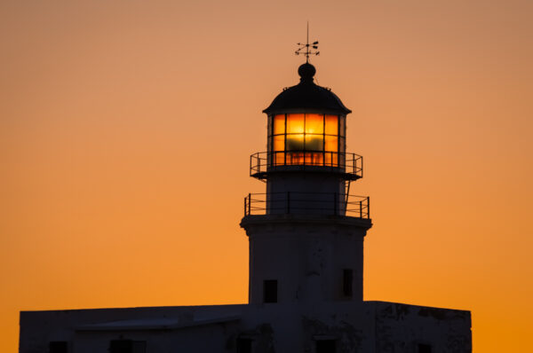 Out of the crowd in Mykonos for beautiful landscape photos Lighthouse glow. 
Armenisti lighthouse at sunset, Mykonos, Cyclades, Greece